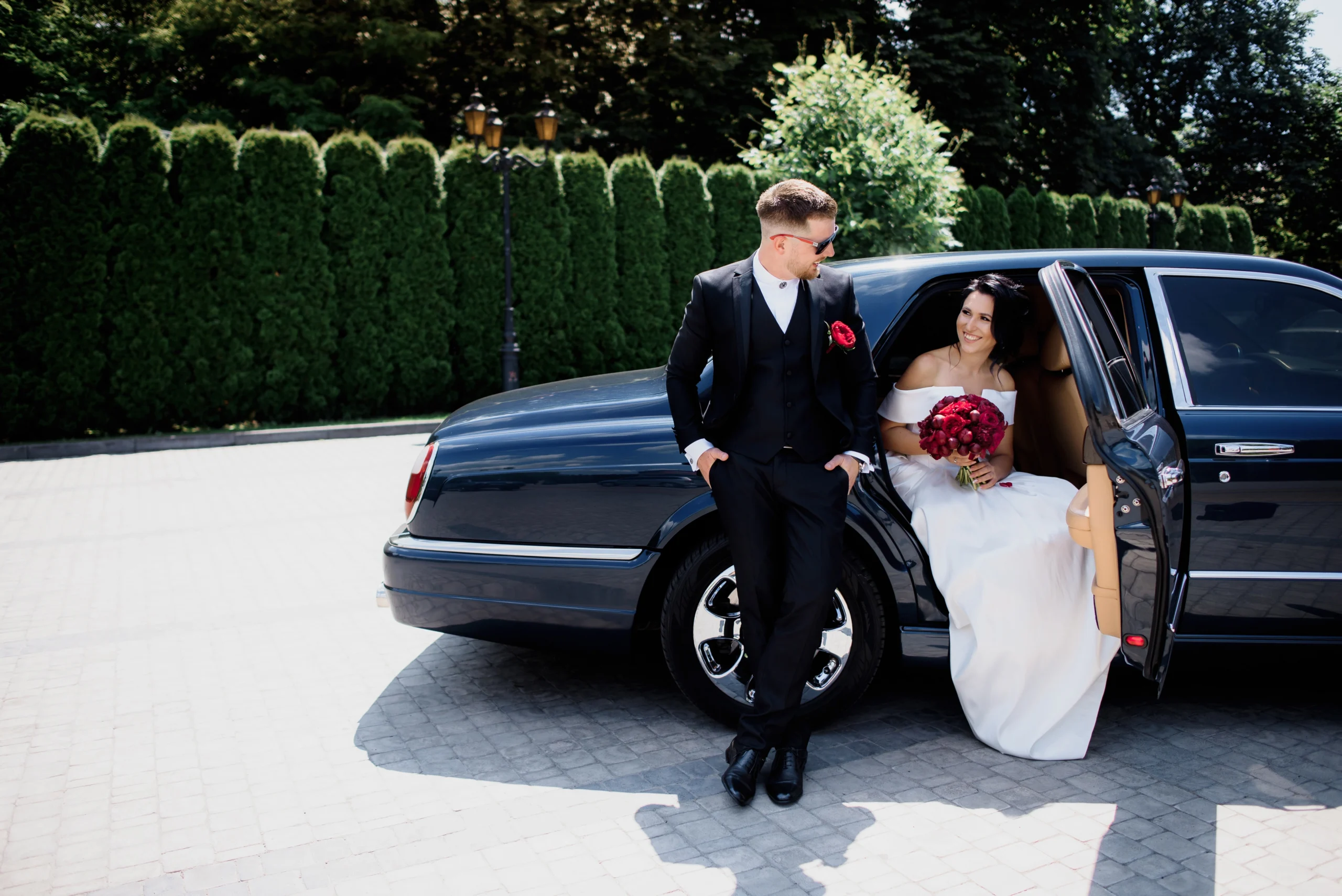 Elegant wedding couple with luxury black car